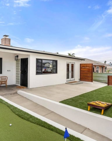 Backyard patio with rattan seating, umbrella, lawn, and laundry room door on right